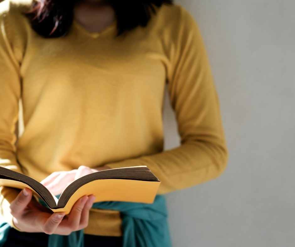 Women in yellow long sleeve shirt reading a book